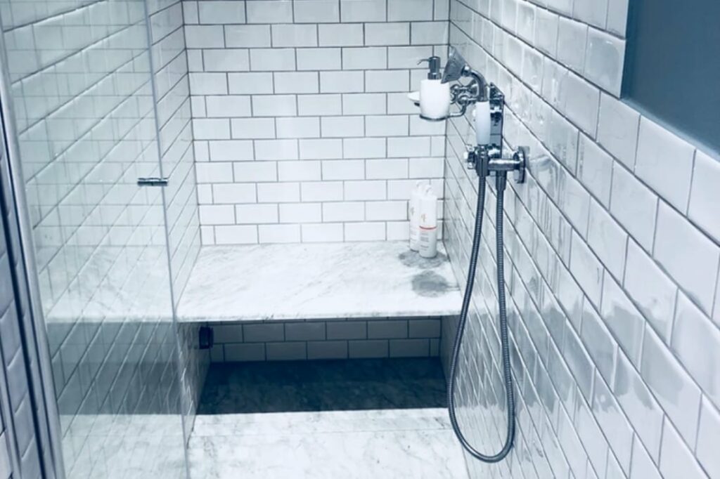 Nyrenoverat badrum med dusch och vitt kakel